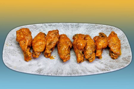 Téléchargez les photos : Composition d'une assiette d'ailes de poulet avec sauce Buffalo sur fond jaune et bleu clair - en image libre de droit