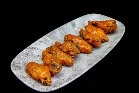 Photo for Composition of a plate of chicken wings with Buffalo sauce on a black background. - Royalty Free Image
