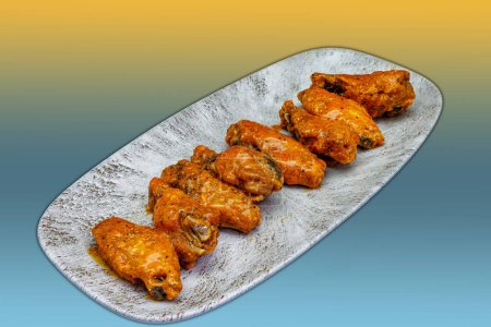 Foto de Composición de un plato de alitas de pollo con salsa Buffalo sobre fondo amarillo y azul claro - Imagen libre de derechos