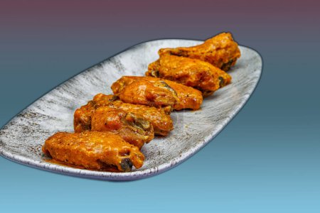Foto de Composición de un plato de alitas de pollo con salsa Buffalo sobre un fondo magenta y azul claro. - Imagen libre de derechos