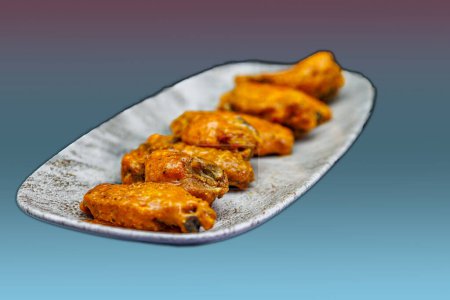Photo for Composition of a plate of chicken wings with Buffalo sauce on a magenta and light blue background. - Royalty Free Image
