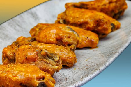 Téléchargez les photos : Composition d'une assiette d'ailes de poulet avec sauce Buffalo sur fond jaune et bleu clair - en image libre de droit