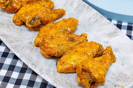 Téléchargez les photos : Composition d'une assiette d'ailes de poulet avec sauce Buffalo sur une nappe à carreaux noir et blanc. - en image libre de droit