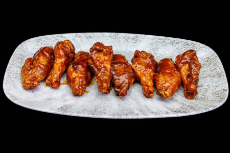 Téléchargez les photos : Composition d'une assiette d'ailes de poulet avec sauce barbecue sur fond noir - en image libre de droit