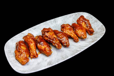 Foto de Composición de un plato de alitas de pollo con salsa barbacoa sobre fondo negro - Imagen libre de derechos