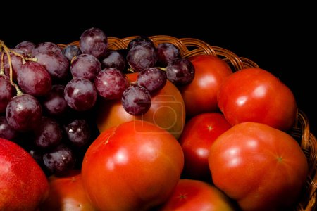 Foto de Composición de peras, tomates y uvas en una cesta - Imagen libre de derechos
