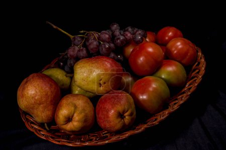 Foto de Composición de peras, tomates y uvas en una cesta - Imagen libre de derechos