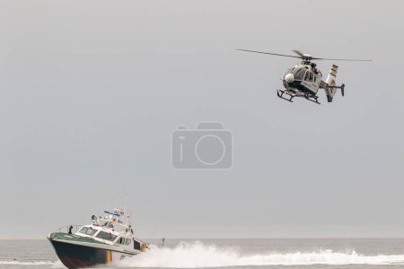 Photo for TORRE DEL MAR, MALAGA, SPAIN-JUL 12: Guardia Civil coast guard patrol and helicopter EC-135 taking part in a exhibition on the 4th airshow of Torre del Mar on July 12, 2019, in Torre del Mar, Malaga, Spain - Royalty Free Image