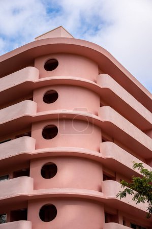 Photo for Honolulu, Hawaii - December 28, 2022: Exterior of a pink, retro art deco style apartment building in the heart of Waikiki. - Royalty Free Image
