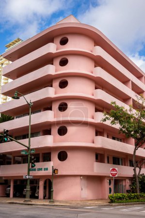 Photo for Honolulu, Hawaii - December 28, 2022: Exterior of a pink, retro art deco style apartment building in the heart of Waikiki. - Royalty Free Image