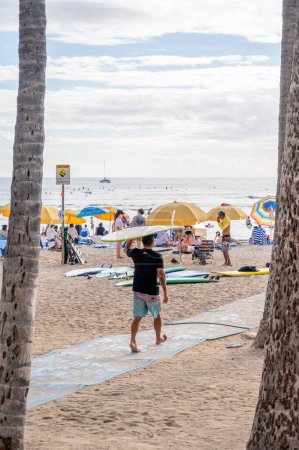 Foto de Honolulu, Hawaii - December 29, 2022: Man carrying a surfboard to Waikiki Beach. - Imagen libre de derechos