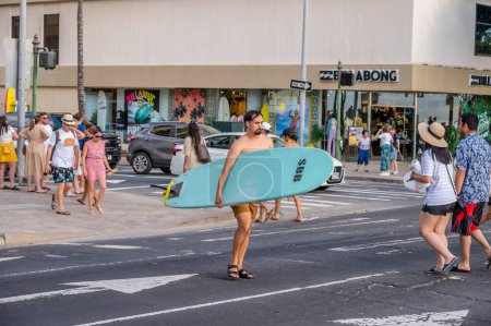 Foto de Honolulu, Hawaii - December 29, 2022: Man carrying a surfboard to Waikiki Beach. - Imagen libre de derechos