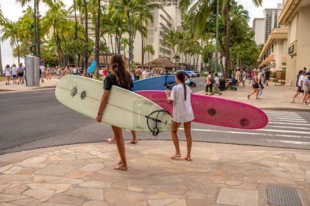 Foto de Honolulu, Hawaii - December 29, 2022: Family carrying  surfboards to Waikiki Beach. - Imagen libre de derechos