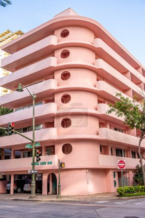 Photo for Honolulu, Hawaii - January 1, 2022: Exterior of a pink, retro art deco style apartment building in the heart of Waikiki. - Royalty Free Image