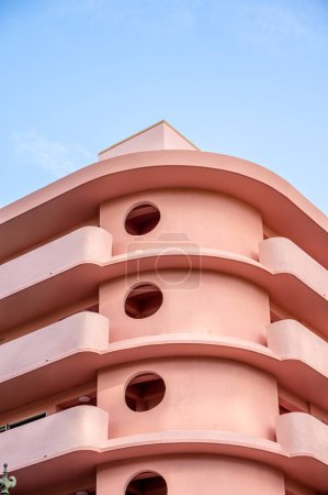 Photo for Honolulu, Hawaii - January 1, 2022: Exterior of a pink, retro art deco style apartment building in the heart of Waikiki. - Royalty Free Image