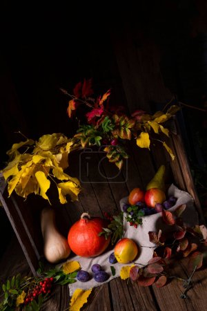 Foto de Varias frutas en una caja de madera con hojas de otoño - Imagen libre de derechos