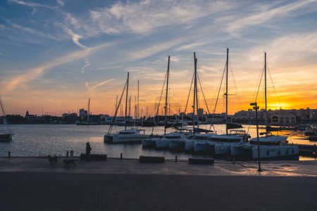 Téléchargez les photos : Yachts avec reflet dans l'eau de mer du port de Valence. Des grues portuaires à l'horizon. Soirée chaude en Espagne. - en image libre de droit
