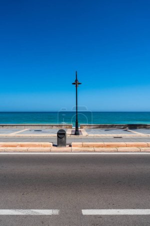 Foto de Composición minimalista con una linterna en el paseo marítimo. Un día soleado y cálido en un resort en España. - Imagen libre de derechos