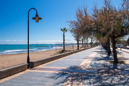 Foto de El paseo marítimo del mar Mediterráneo en un día soleado en primavera. Palmeras y bancos entre elegantes casas en la provincia de Castellón - Imagen libre de derechos