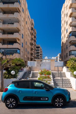 Foto de Coche frente a casas modernas en el terraplén del mar Mediterráneo en un soleado día de primavera. Palmeras entre casas con estilo en la provincia de Castell n - Imagen libre de derechos