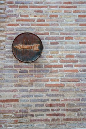 Foto de Señal de tráfico oxidada en una pared de ladrillo. La flecha a la izquierda en el círculo muestra la dirección del movimiento Foto de alta calidad - Imagen libre de derechos