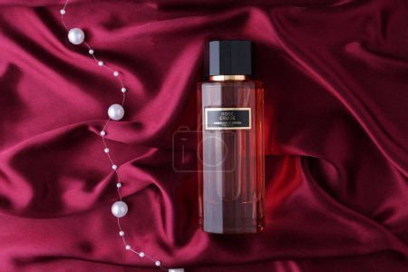 Photo for Perfume bottle . Rose Cruise , Carolina Herrera Perfume bottle  with pearls over red silk background view. - Royalty Free Image