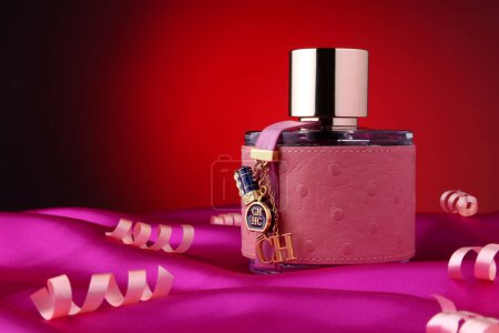 Téléchargez les photos : Flacon de parfum .Carolina Herrera CH avec serpentine sur fond rouge - en image libre de droit