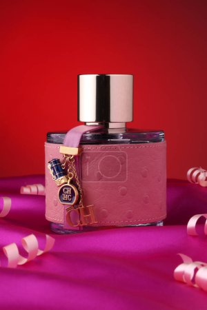 Téléchargez les photos : Flacon de parfum .Carolina Herrera CH avec serpentine sur fond rouge - en image libre de droit