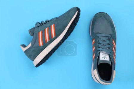 Photo for Jeddah, Saudi Arabia - 25th July, 2020: ADIDAS sport shoe, on blue background. Product shot. Adidas is a German corporation that designs and manufactures sports shoes, clothing and accessories - Royalty Free Image