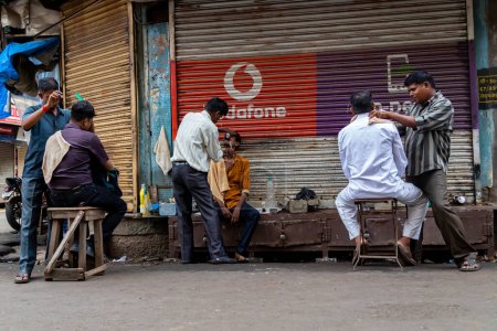 Téléchargez les photos : Mumbai, Maharashtra Inde 12 août 2019 Un salon de coiffure dans la rue du Fort Market près de la gare Queen Victoria. Il offre non seulement des coupes et des rasages rapides et bon marché, mais fonctionne également comme un centre communautaire. - en image libre de droit
