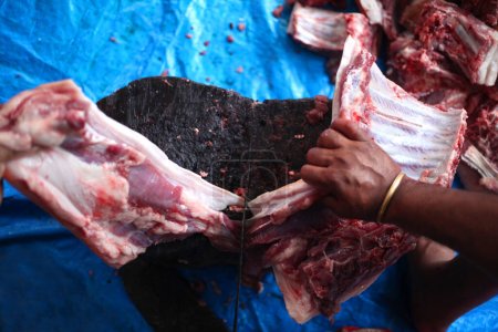 Foto de Carnicero cortando carne cruda con un cuchillo a la mesa en el matadero - Imagen libre de derechos