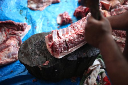 Foto de Carnicero cortando carne cruda con un cuchillo a la mesa en el matadero - Imagen libre de derechos