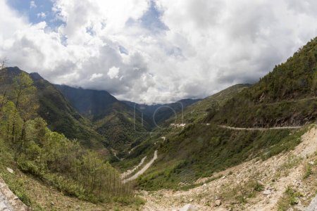 Foto de Pendientes de altas montañas cubiertas de espeso bosque virgen y cubiertas de nubes cerca del pequeño pueblo de senge cerca de Tawang en el oeste de Arunachal Pradesh, India. - Imagen libre de derechos