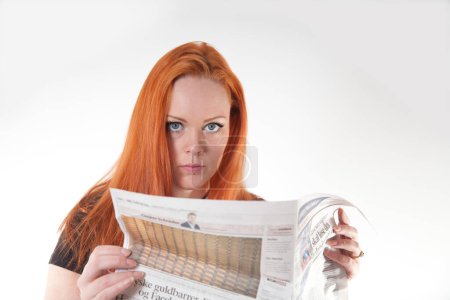 Photo for Woman with red hair readind a newspaper shot in studio with white background - Royalty Free Image