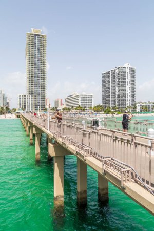Photo for Sunny Isles Beach, USA - August 17, 2014: people at pier on Jade beach in Sunny Isles Beach, USA. Jade Beach and Ocean were completed in 2009 with a elevation of 549 feet located at 170th Street. - Royalty Free Image