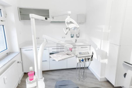 Téléchargez les photos : Armoire dentaire moderne avec lampe, chaise et équipement complet - en image libre de droit