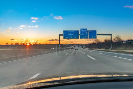 Photo for Frankfurt, Germany - February 10, 2021: german highway in sunset with driving cars and sun reflection - Royalty Free Image