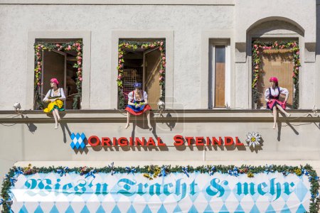 Téléchargez les photos : Munich, Allemagne - 7 avril 2009 : marionnettes en costumes bavarois assis à la fenêtre avec publicité pour des custumes bavaroises originales. - en image libre de droit