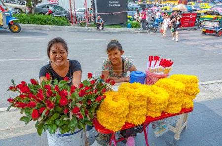 Téléchargez les photos : Bangkok, Thaïlande - 11 mai 2009 : Des femmes avec des fleurs à une petite table au centre-ville de Bangkok gagnent de l'argent en vendant des fleurs dans la rue. - en image libre de droit