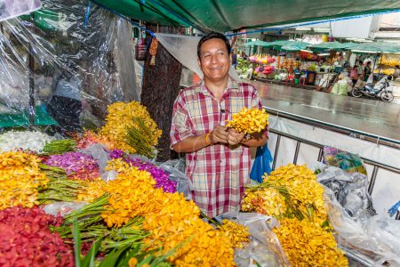 Photo for Bangkok, Thailand - May 12, 2009: senior woman sells orange holy flowers to the local people at the night market Pak khlong Talat in Chinatown, Bangkok. - Royalty Free Image