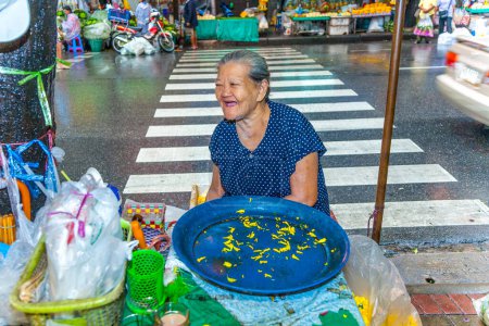 Téléchargez les photos : Bangkok, Thaïlande - 12 mai 2009 : Une femme âgée vend des fleurs oranges sacrées à la population locale au marché de nuit Pak khlong Talat à Chinatown, Bangkok. - en image libre de droit