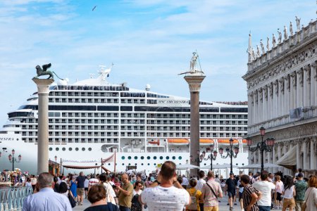 Photo for Venice, Italy - July 3, 2021: Cruise ship MSC ORCHESTRA in the Venetian lagoon with gondolas and tourists in the foreground in Venice. Venice is a major tourist destination in Italy. - Royalty Free Image