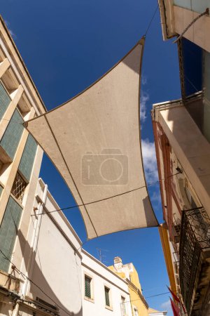 Foto de Facade of old buildings in the old town of Faro, Portugal, Algarve in panoramic view with sun shadow - Imagen libre de derechos