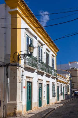 Foto de Faro, Portugal - October 3, 2020: historic building  in the old town of Faro with traditional narrow small houses, iron balconies and white painted walls in Portugal. - Imagen libre de derechos