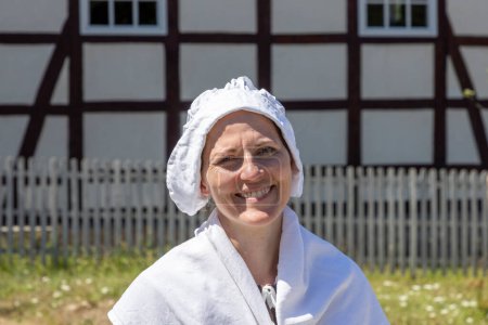 Téléchargez les photos : Neu Anspach, Germany - August 6, 2020: young attractive woman in old traditional clothes demonstrates former traditional clothing in the Hessenpark in Germany. - en image libre de droit