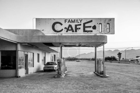 Téléchargez les photos : Naufrage d'une voiture dans une station-service abandonnée dans le village désertique de Desert Center au coucher du soleil - en image libre de droit