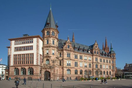 Foto de Wiesbaden, Alemania - 2 de marzo de 2023: personas en la plaza del mercado con el histórico ayuntamiento bajo el cielo azul. - Imagen libre de derechos