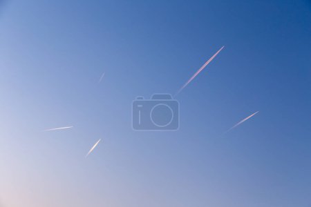 Téléchargez les photos : Beaucoup de traînées d'avion au soleil tôt le matin au ciel - en image libre de droit