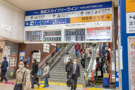 Téléchargez les photos : Tokyo, Japon - 17 mars 2023 : personnes à la station de métro Tokyo. La signalisation en japonais et en anglais montre aux touristes la direction et l'horaire du métro. - en image libre de droit