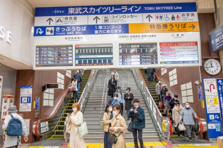 Téléchargez les photos : Tokyo, Japon - 17 mars 2023 : personnes à la station de métro Tokyo. La signalisation en japonais et en anglais montre aux touristes la direction et l'horaire du métro. - en image libre de droit